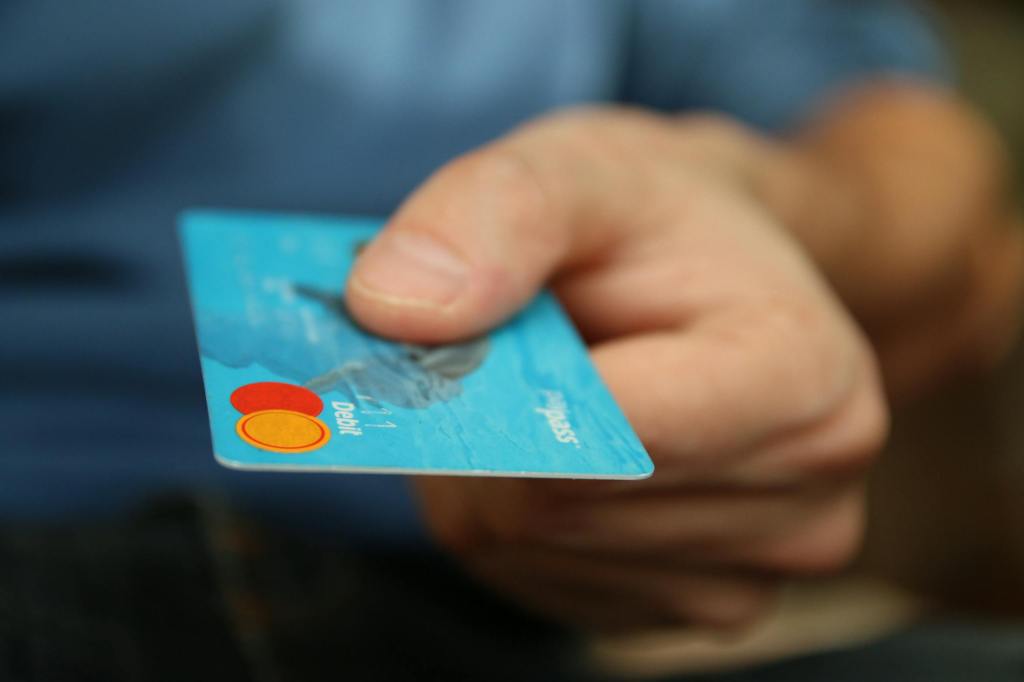 Person Holding Debit Card as their consider how to improve their credit score